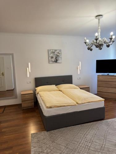 a bedroom with a bed and a television and a chandelier at Barokk Hotel in Hegyeshalom