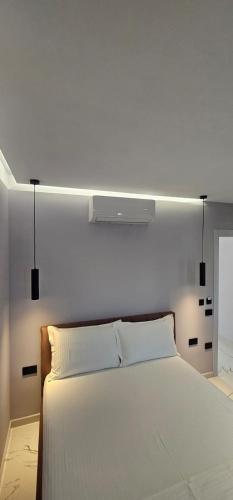 a bedroom with a white bed with lights above it at Saranda's Crown in Sarandë