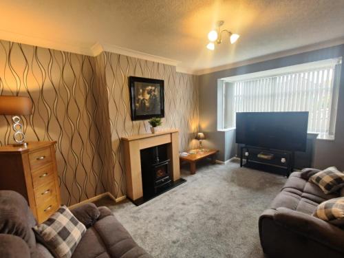 a living room with a couch and a flat screen tv at Chic 2-Bed Loft Bungalow, Cleveleys, Near Beach in Blackpool
