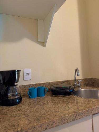 a kitchen counter with a sink and a mixer at Studio pé na areia, vista, internet e ar in Macaé