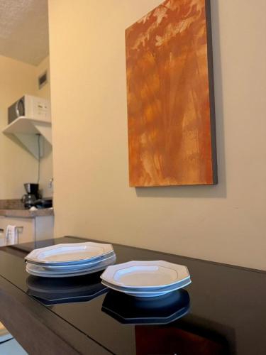 two white plates sitting on a counter in a kitchen at Studio pé na areia, vista, internet e ar in Macaé