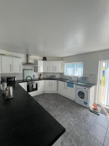 a kitchen with white cabinets and a black counter top at Concord House, 3 bedroom house, 2 baths in Rainham, in Dagenham Dock