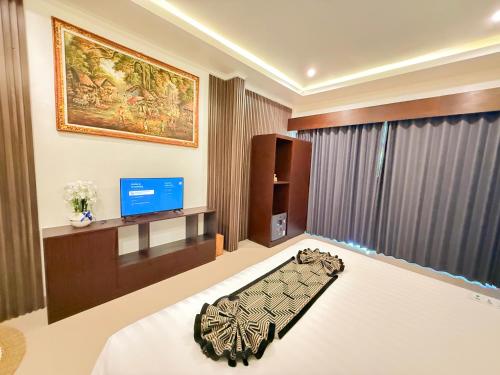 a bedroom with a bed and a television in it at Kelingking Tropical in batumadeg