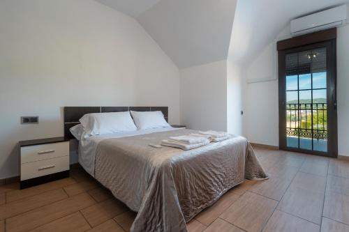 a white bedroom with a bed and a window at Villa Oasis in Lora del Río