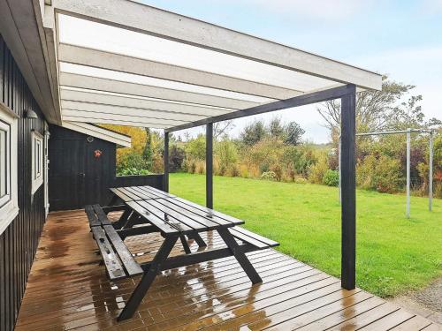 a wooden deck with a picnic table under awning at Luxury Pool House in Lonstrup - By Traum Ferienwohnungen in Lønstrup