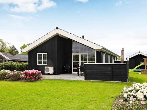 a black house with a patio and a yard at 10 person holiday home in Ansager-By Traum in Ansager