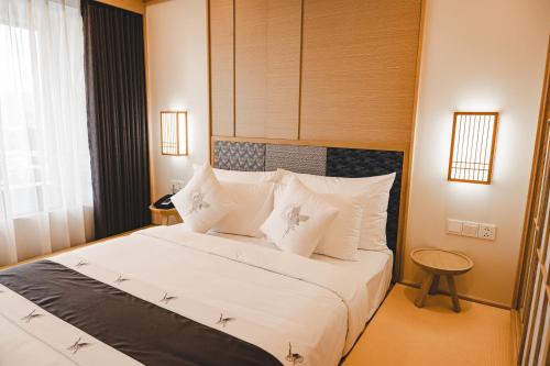 a bedroom with a large white bed with white pillows at Lynn Times Thanh Thuy Onsen Hot Spring in La Phu