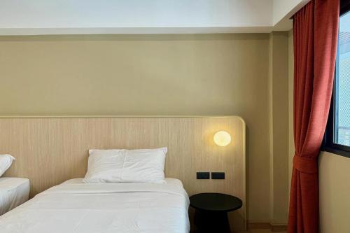 a bedroom with a white bed and a window at Parcel Hotel Bangkok in Bangkok