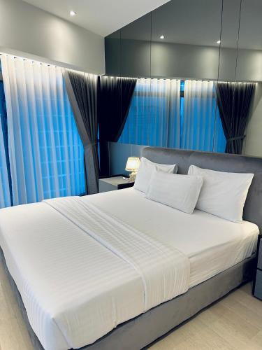 a bedroom with a large white bed with blue curtains at Eaton Residences By Classic in Kuala Lumpur