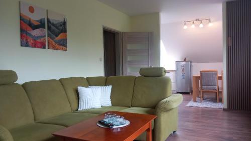 a living room with a green couch and a table at Apartman Lunette in Tatranska Strba
