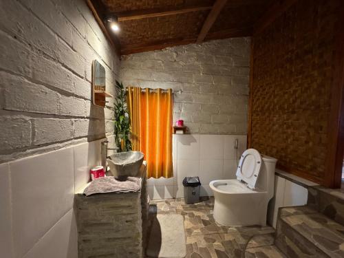 a bathroom with a toilet and an orange curtain at Hide and Seek in Tetebatu