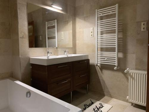 a bathroom with a sink and a tub and a mirror at Centrum Vendégház in Miskolc