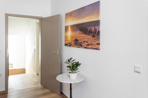 a painting hanging on a wall with a plant on a table at Walnut Tree Apart in Bergisch Gladbach