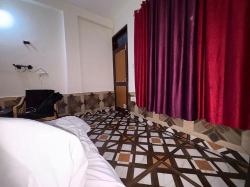 a bedroom with a bed and a red curtain at Hotel B2B 2500 Rs With Bkf & Dinner , Mounatin View And Balcony in Manāli
