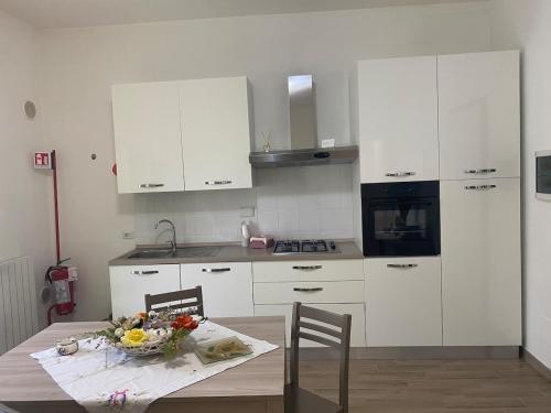 a kitchen with white cabinets and a table with flowers on it at Andrew House in Ciampino