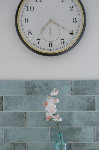 a clock on a wall with a vase with a flower at Baltic Studio 15 minutes from the Beach by Noclegi Renters in Gdańsk