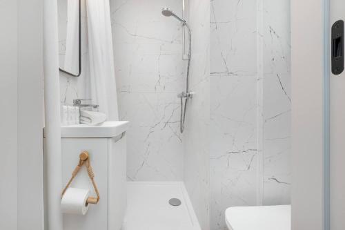 a white bathroom with a shower and a toilet at Baltic Studio 15 minutes from the Beach by Noclegi Renters in Gdańsk