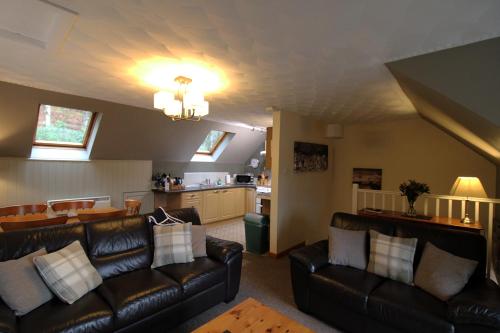 a living room with leather couches and a kitchen at Corrieview Lodges in Spean Bridge