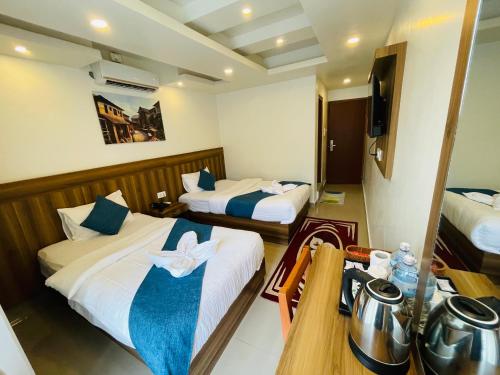 a hotel room with two beds and a television at Novetel Boutique Home in Pokhara