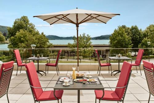 a patio with tables and chairs and an umbrella at Falkensteiner Schlosshotel Velden – The Leading Hotels of the World in Velden am Wörthersee