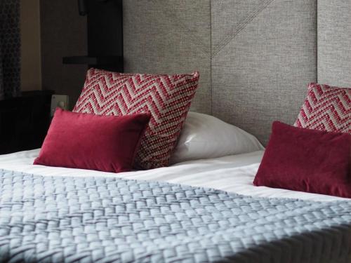 a white bed with two red pillows on it at Santa's Hotel Santa Claus in Rovaniemi