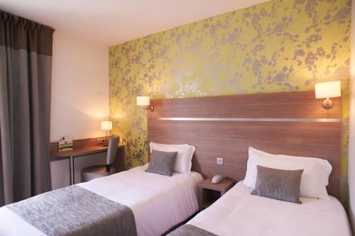 a hotel room with two beds and a desk at The Originals City, le Beaujoire, Nantes - FACE Parc Expo et FACE Stade Beaujoire in Nantes