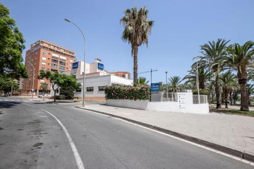 an empty street with palm trees and a building at Travelodge Alicante Puerto in Alicante