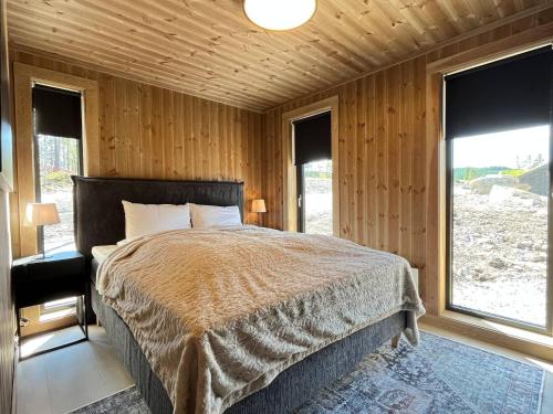 ein Schlafzimmer mit einem Bett in einem Zimmer mit Fenstern in der Unterkunft Skogsbu - Stylish, Close to Ski centers and hiking trails in Nystølen