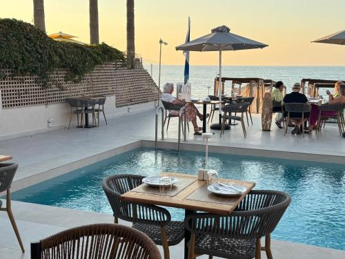 ein Restaurant mit einem Tisch und Stühlen neben einem Pool in der Unterkunft Τhe Noverian Antama Organic Beach Resort Chania in Agia Marina