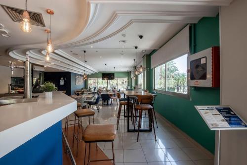 a restaurant with a bar with green walls and stools at Travelodge Alicante Puerto in Alicante
