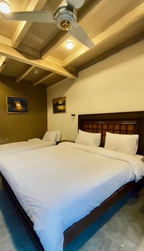 two beds in a room with white sheets at Escape Retreat Hunza in Karimabad Hunza