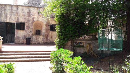 un edificio con una jaula colgando de un árbol en Trulli delle Rose - Selva di Fasano, en Selva di Fasano