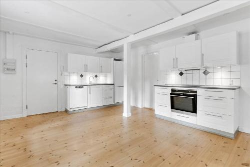 a white kitchen with white cabinets and a wooden floor at LD Central Lejlighed Odense C in Odense