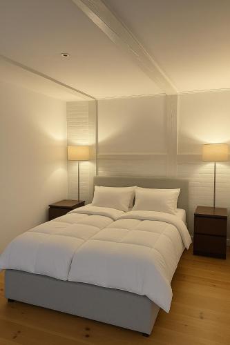 a bedroom with a large white bed with two lamps at LD Central Lejlighed Odense C in Odense