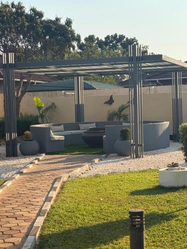 a patio with a couch under a pergola at Java Tree Cottage in Lusaka
