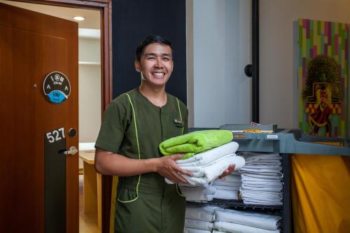 a man in a room holding a pile of towels at MaxOneHotel Tidar Surabaya in Surabaya