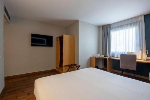 a hotel room with a white bed and a desk at Travelodge Alicante Puerto in Alicante