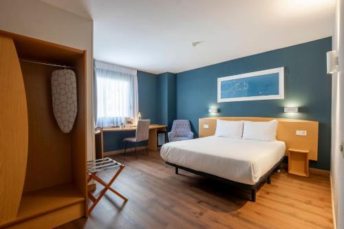 a hotel room with a bed and a desk and a table at Travelodge Alicante Puerto in Alicante