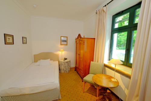 a bedroom with a bed and a table and a window at Hotel Gut Klostermühle natur resort & medical spa in Alt Madlitz