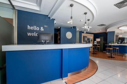 a lobby with a blue wall with a counter at Travelodge Alicante Puerto in Alicante