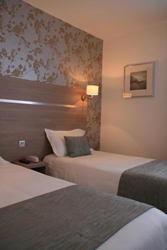 a hotel room with two beds and a lamp at The Originals City, le Beaujoire, Nantes - FACE Parc Expo et FACE Stade Beaujoire in Nantes