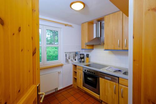 a kitchen with wooden cabinets and a stove top oven at Hotel Gut Klostermühle natur resort & medical spa in Alt Madlitz