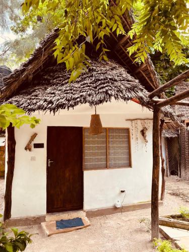 a house with a thatched roof and a door at Mpole Bungalows in Michamvi