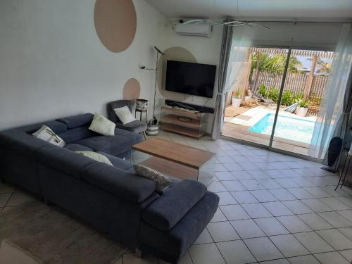 a living room with a couch and a tv at Ylang Ylang in Saint-Leu