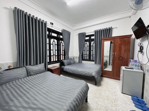 a bedroom with two beds and a tv in it at Lucia Home Đà Lạt in Da Lat