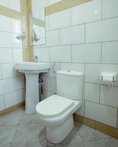 a white bathroom with a toilet and a sink at Sarnah Apartments in Arusha