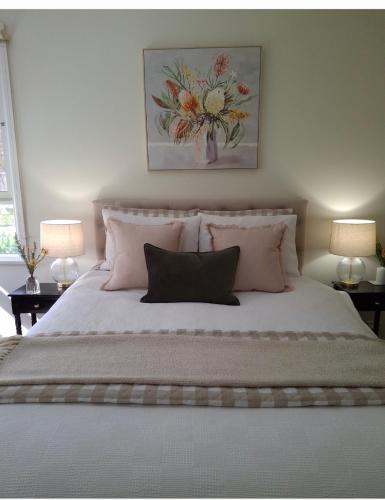 a bedroom with a large bed with pink pillows at HUNTER COTTAGE EUROA - "A great weekend escape" in Euroa