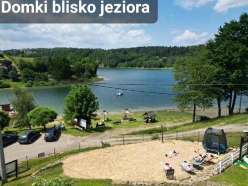 Una vista de un lago con gente en una playa. en Domki Cypel Zawóz, en Zawóz