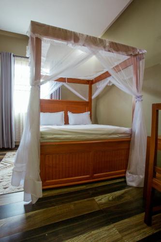a wooden bed with a canopy in a room at Sarnah Apartments in Arusha