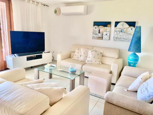 a living room with white furniture and a flat screen tv at Villa Starlight vista mare La Caletta in Santa Lucia